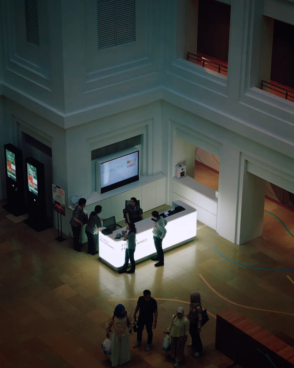 Vista cenital de un stand con mostrador iluminado, pantallas y visitantes (foto de ejemplo)