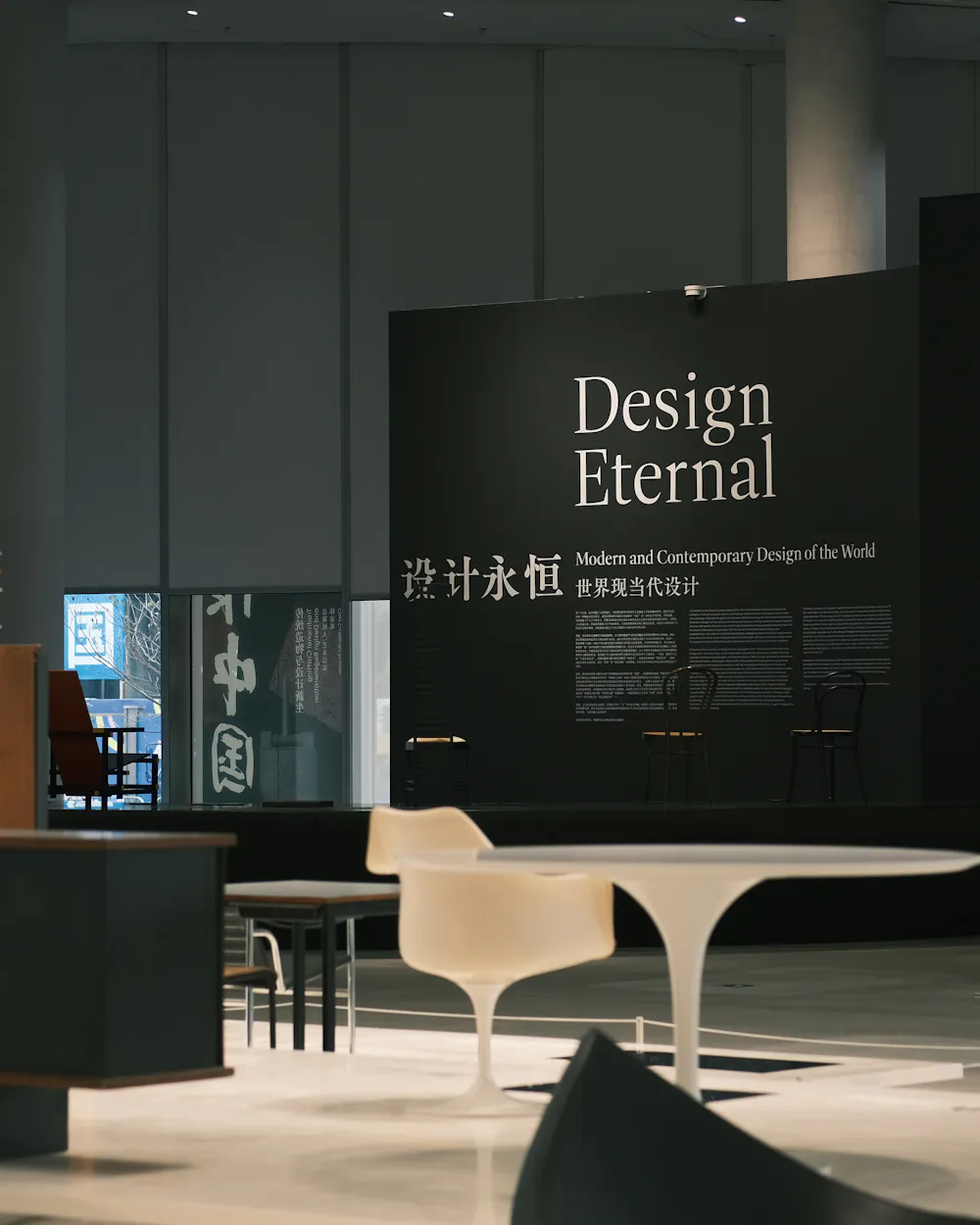 Stand oscuro con rótulo, mesa y sillas de diseño en una feria (foto de ejemplo)
