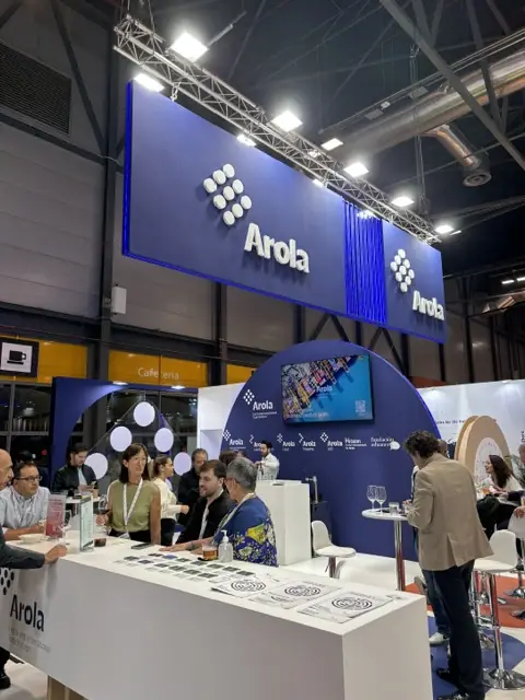 Arola stand with large blue header, bar and high tables