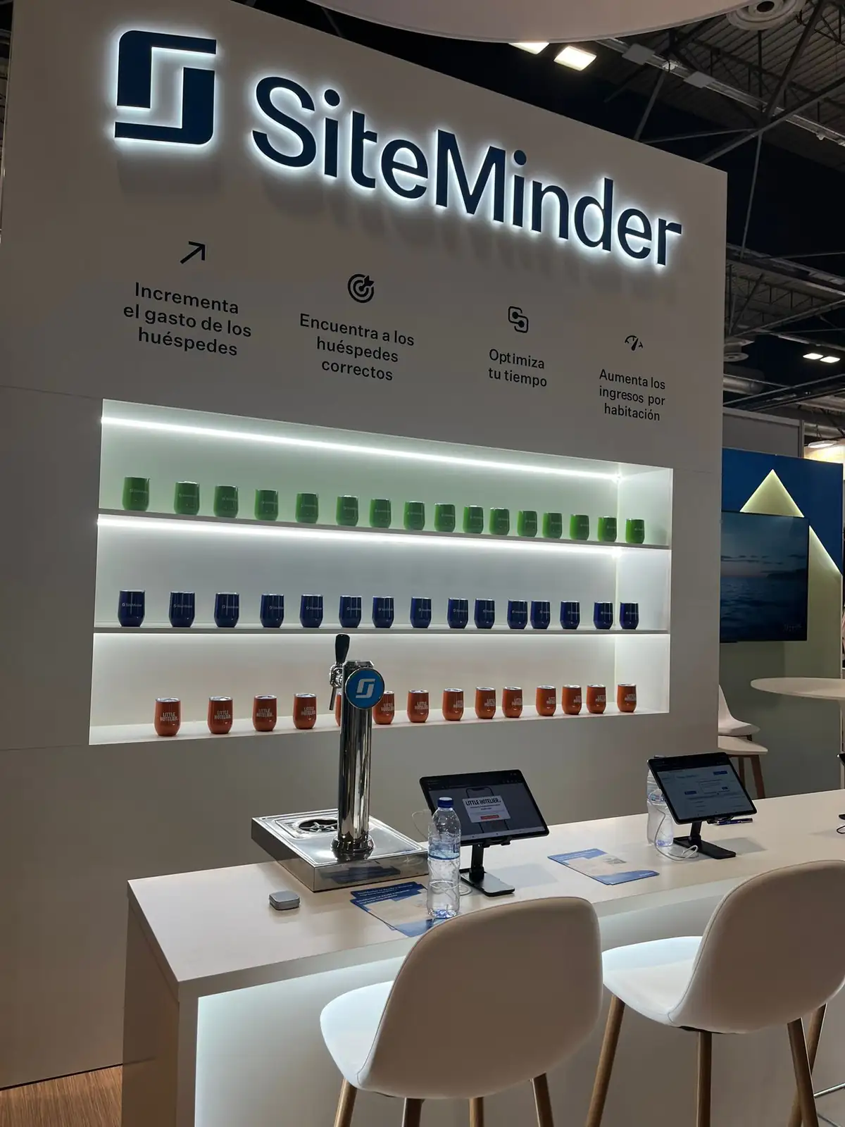 SiteMinder stand with backlit 3D lettering, lit shelving and beer tap